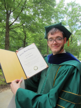 A hat, a hood, and a large document to commemorate the end of 23 years of school.
